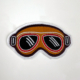 Embroidered Racing Relics patch shaped like vintage racing goggles.